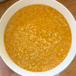 A bowl of soup mini star-shaped pasta in orange vegetable broth