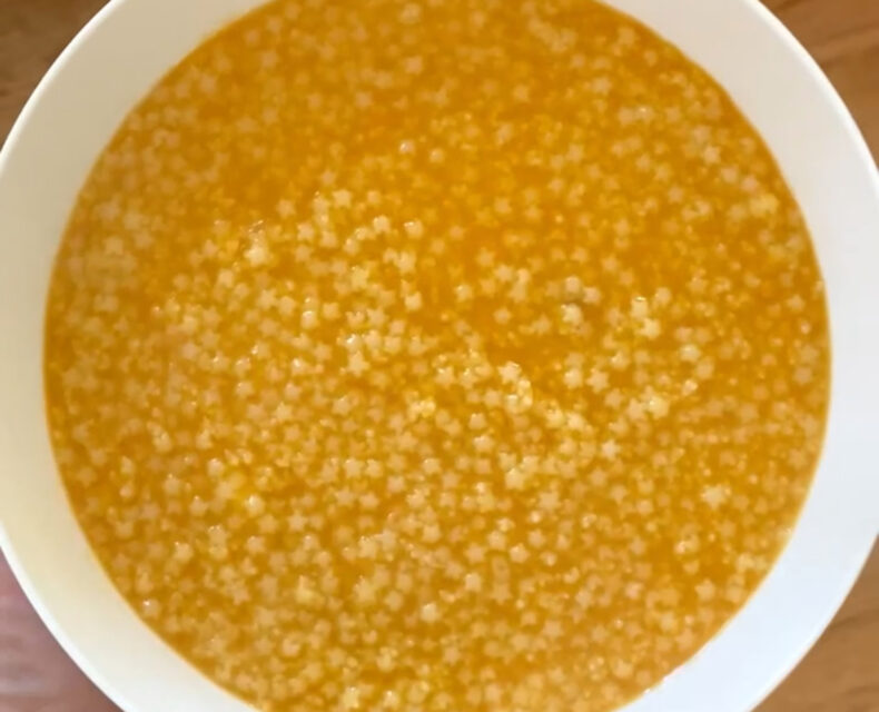 A bowl of soup mini star-shaped pasta in orange vegetable broth