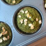 A picture of a muffin pan with green kale oat muffins with whole oats sprinkled on top