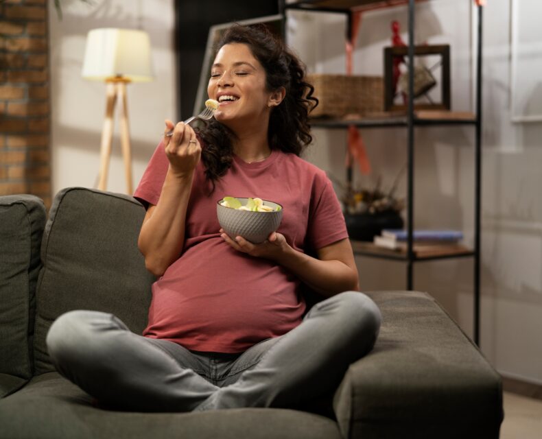 pregnant woman sitting on couch eating healthy pregnancy and postpartum snack