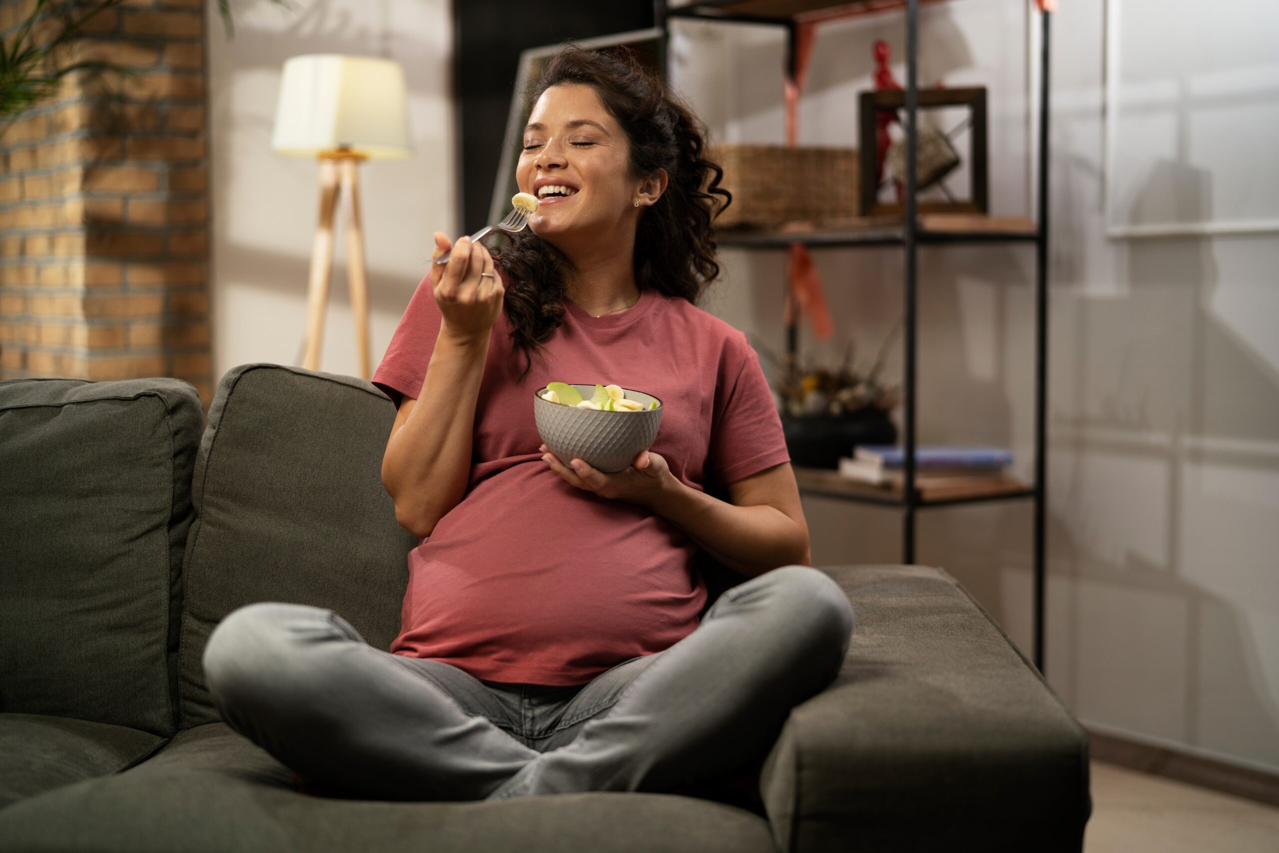 pregnant woman sitting on couch eating healthy pregnancy and postpartum snack