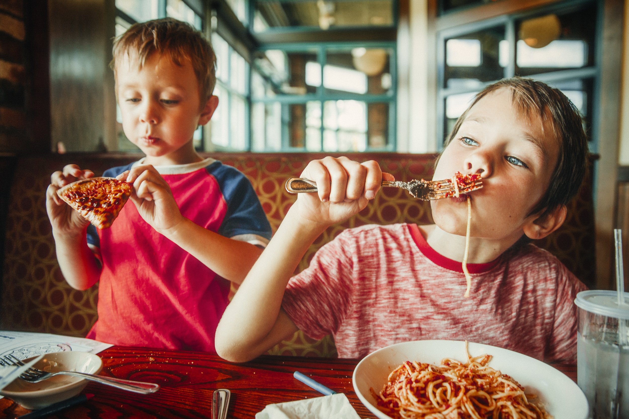 2 young boys eating family style meal at a table